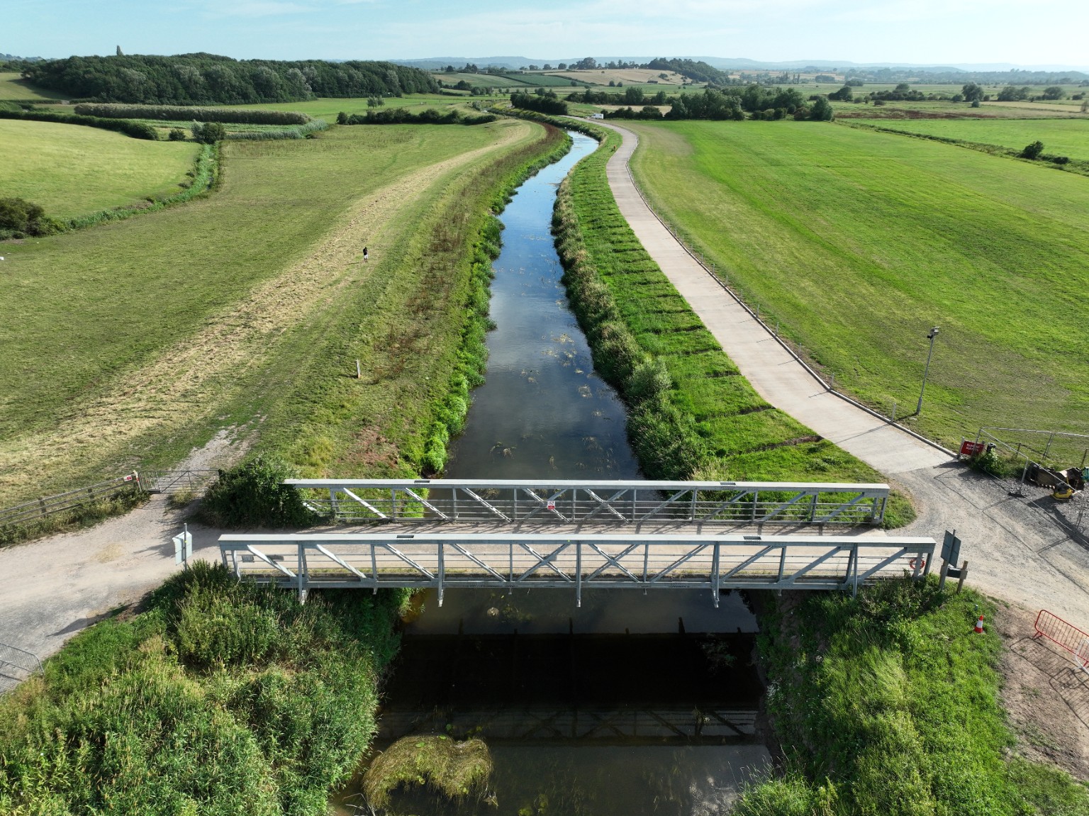 Drone photograph of a bridge over a waterway surrounded by green fields
